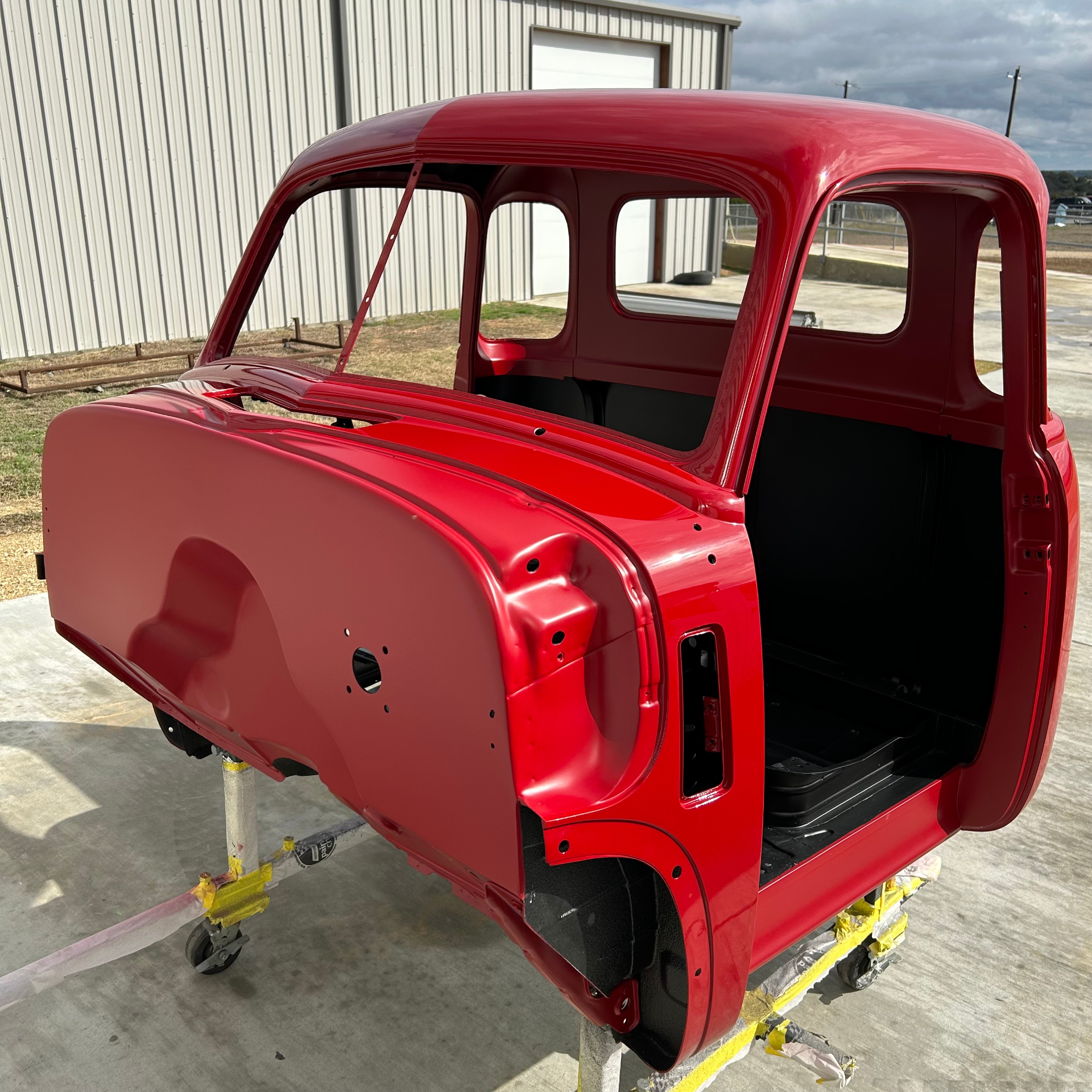 Cab out in the sun after color — red paint catching Texas light for the first time.