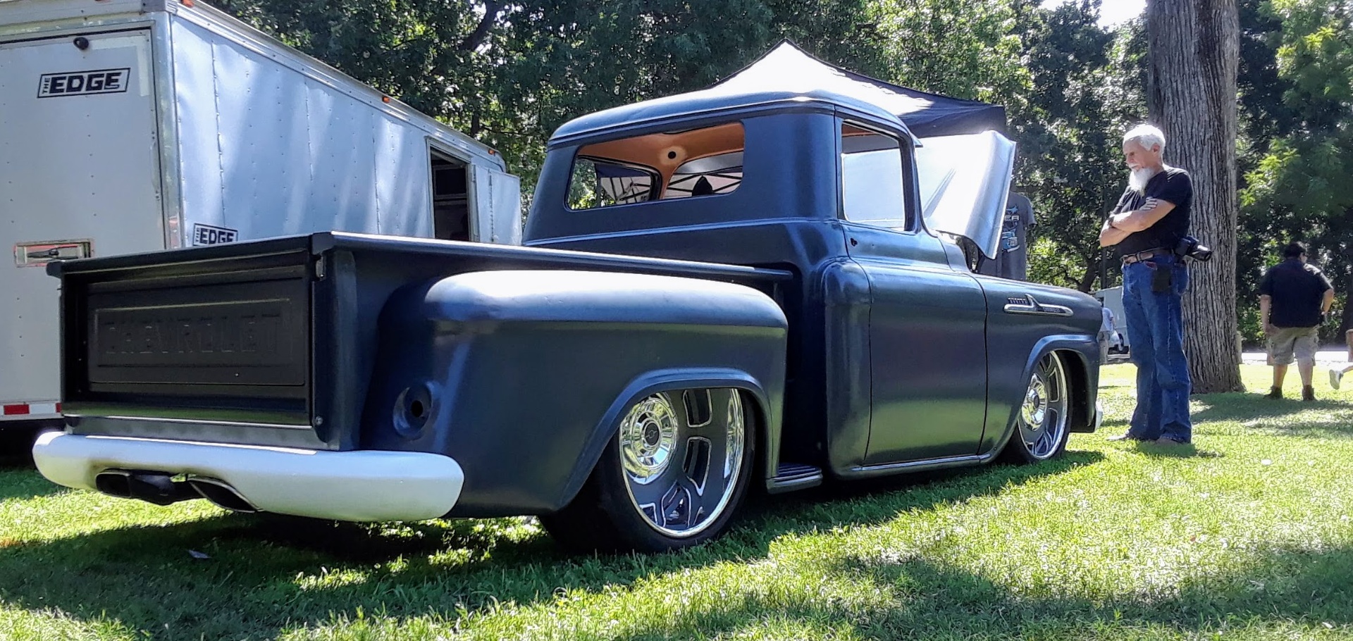 Rear three-quarter in the park — epoxy primer over finished body work, sitting on polished wheels.