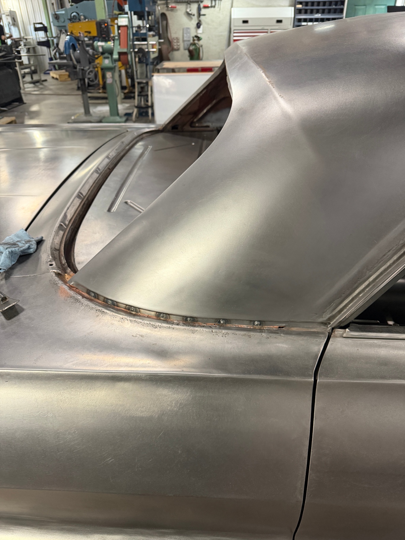 New two-door roof welded in — plug-weld beads along the pillar transition.