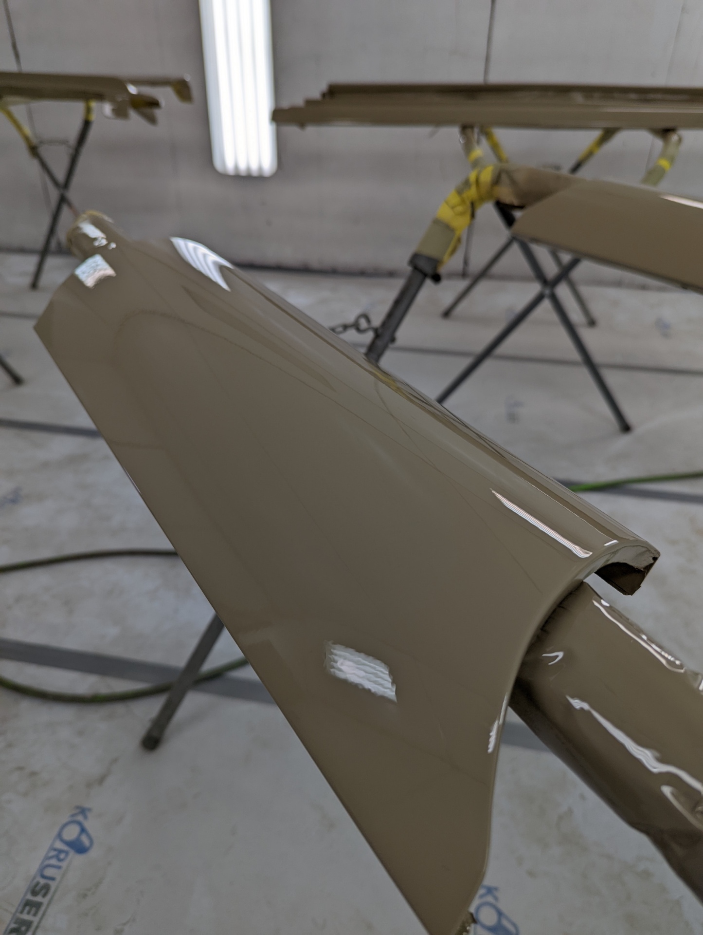 Wet base coat on a fender edge — reflections telling the truth about the block work.
