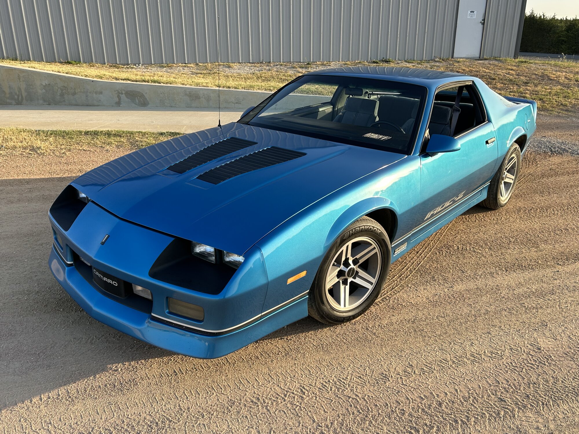 Evening light back at the shop. Original paint, factory 16-inch IROC wheels, louvered hood.