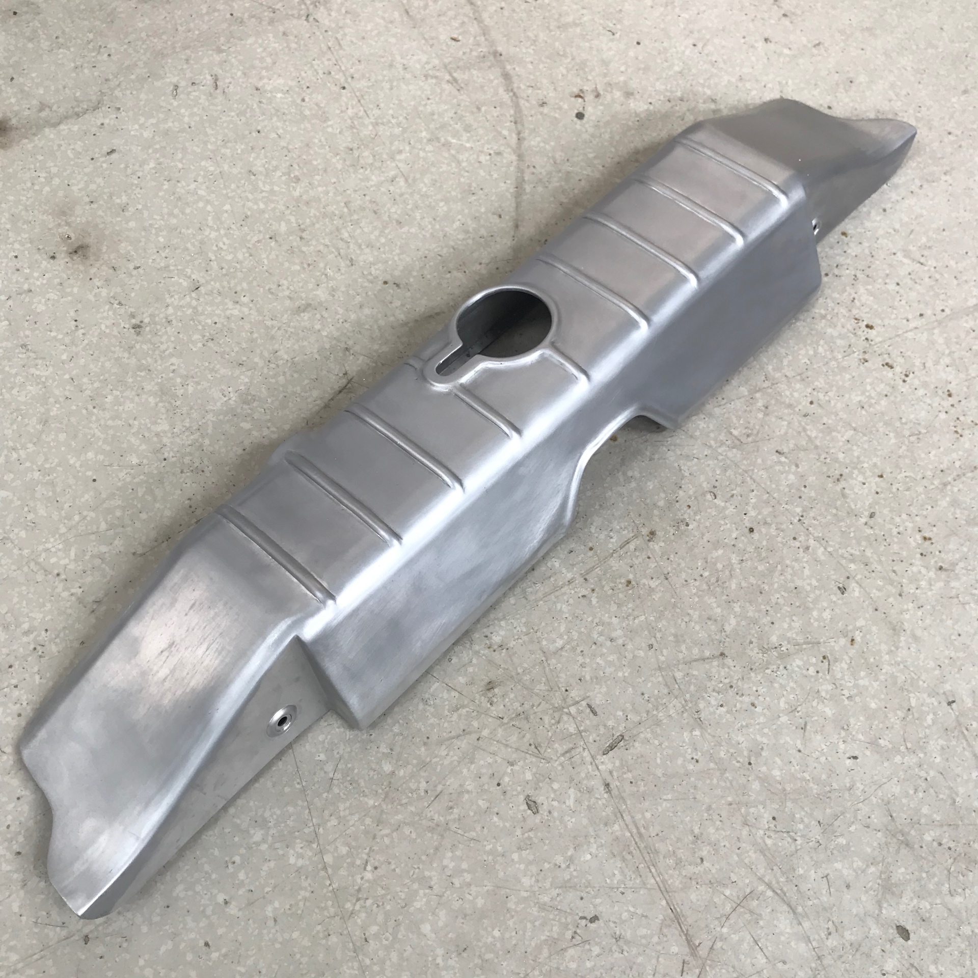 Radiator cover off the car — beaded top, filler neck cutout, contoured ends.