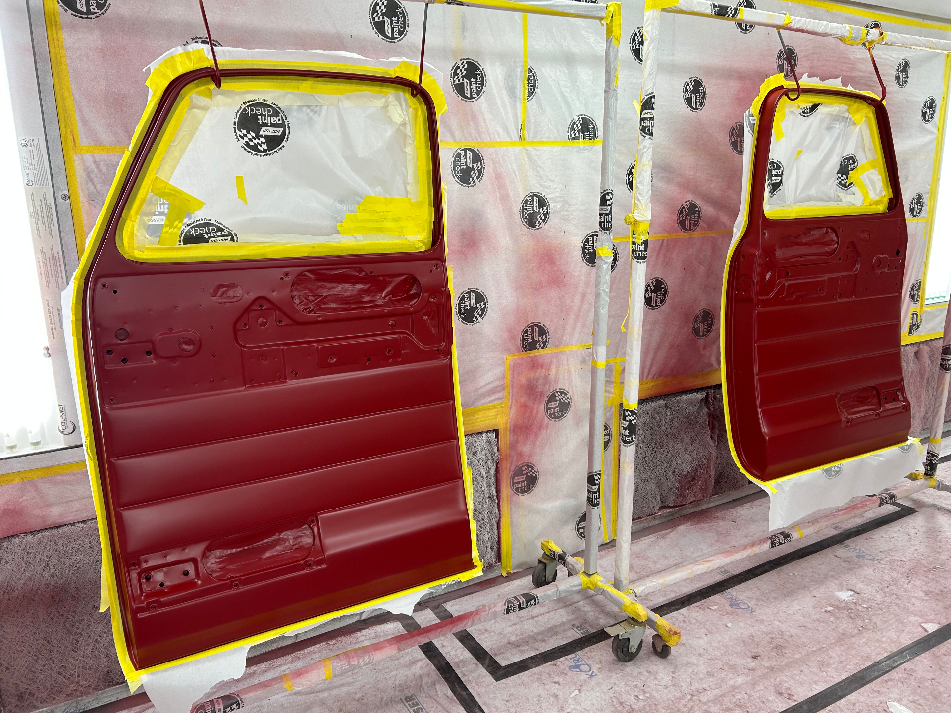 Both doors hung and masked in the booth — inner shells and jambs sprayed body color.