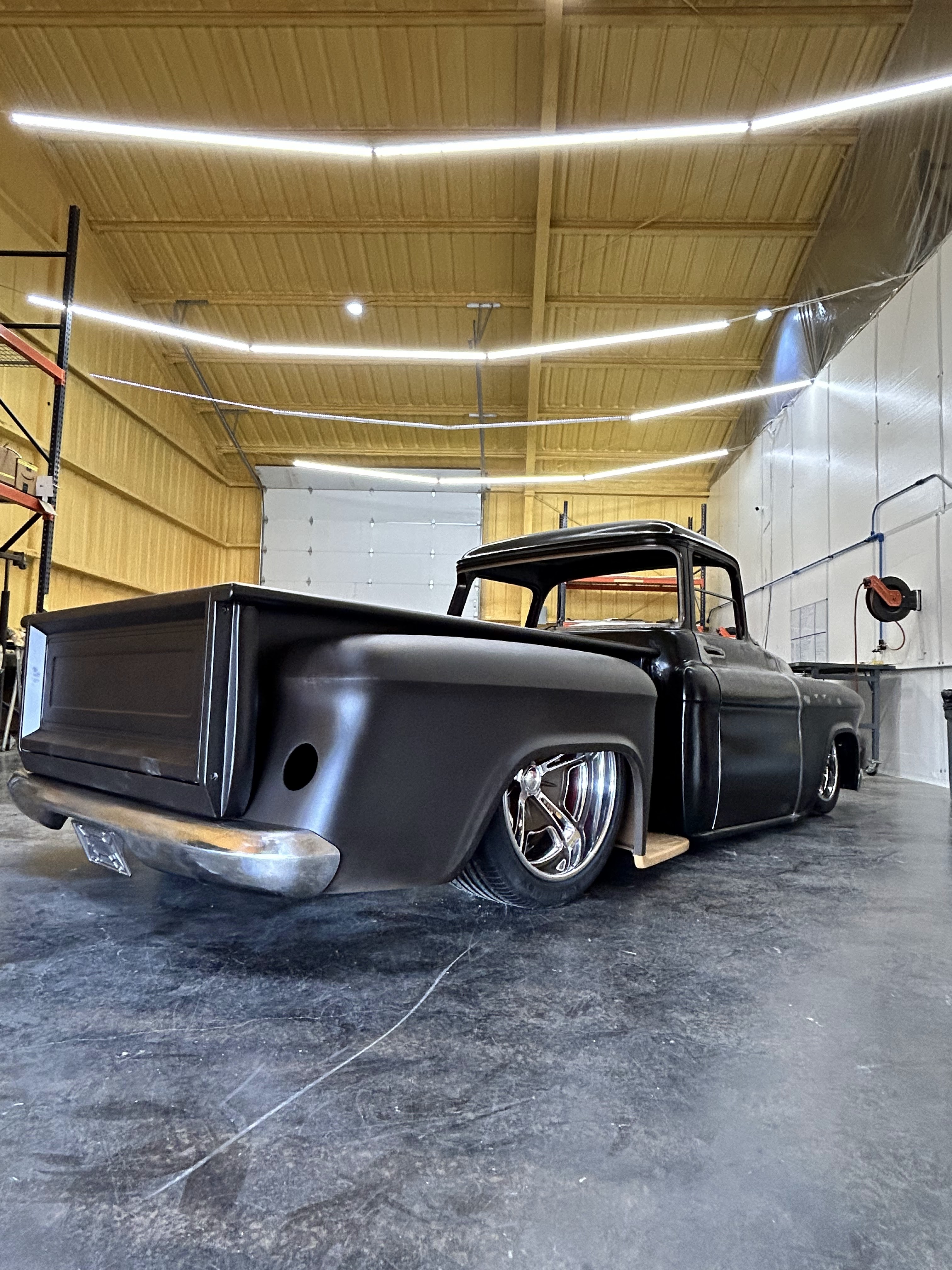 Slammed stance from the rear quarter — bed and cab in primer.
