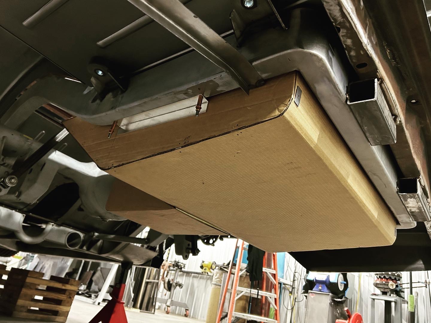 First-pass cardboard mockup taped up under the car to prove the overall envelope around the chassis and rear end.
