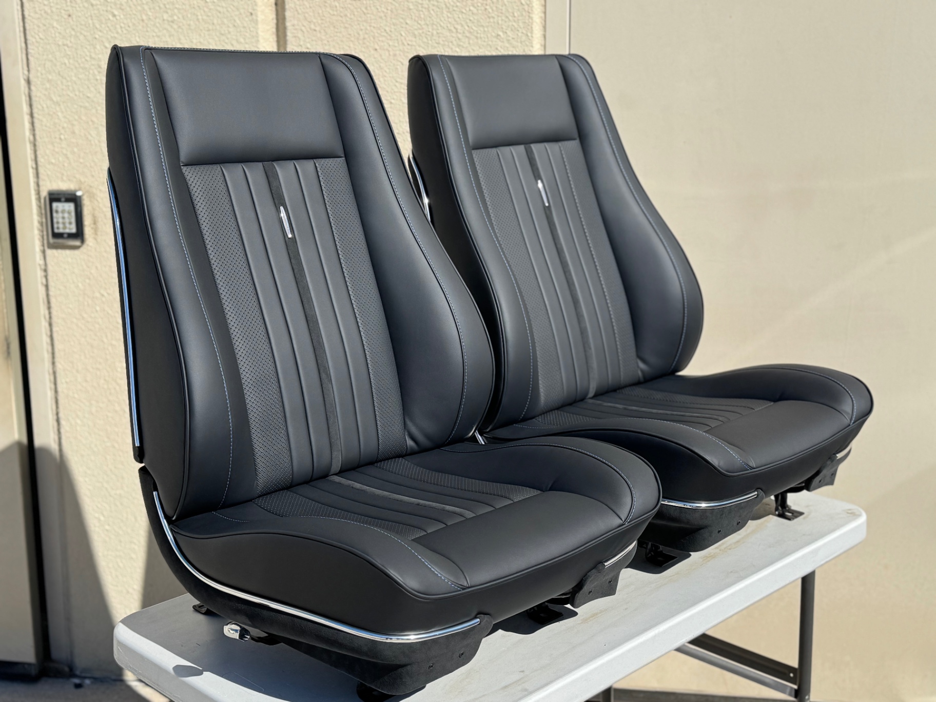 Finished front buckets — reshaped, perforated inserts, Alcantara center stripe, contrast blue stitching.