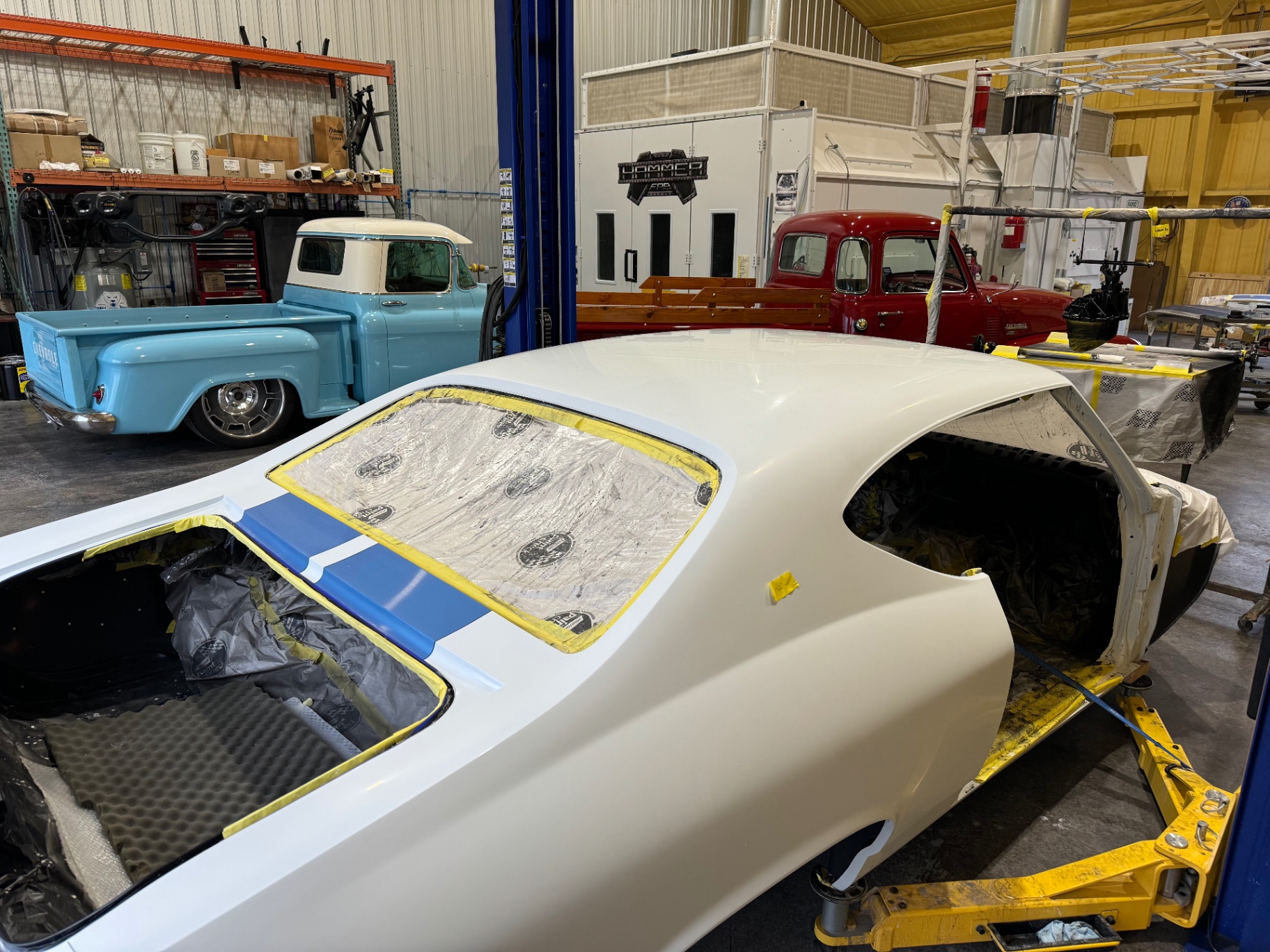 Body in the paint shop — blue stripes over white, masked for color sanding and polish.
