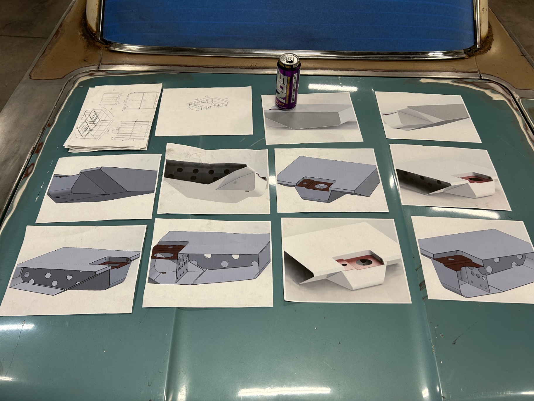 SolidWorks screenshots printed and laid out on the hood — every panel modeled before a single cut was made.