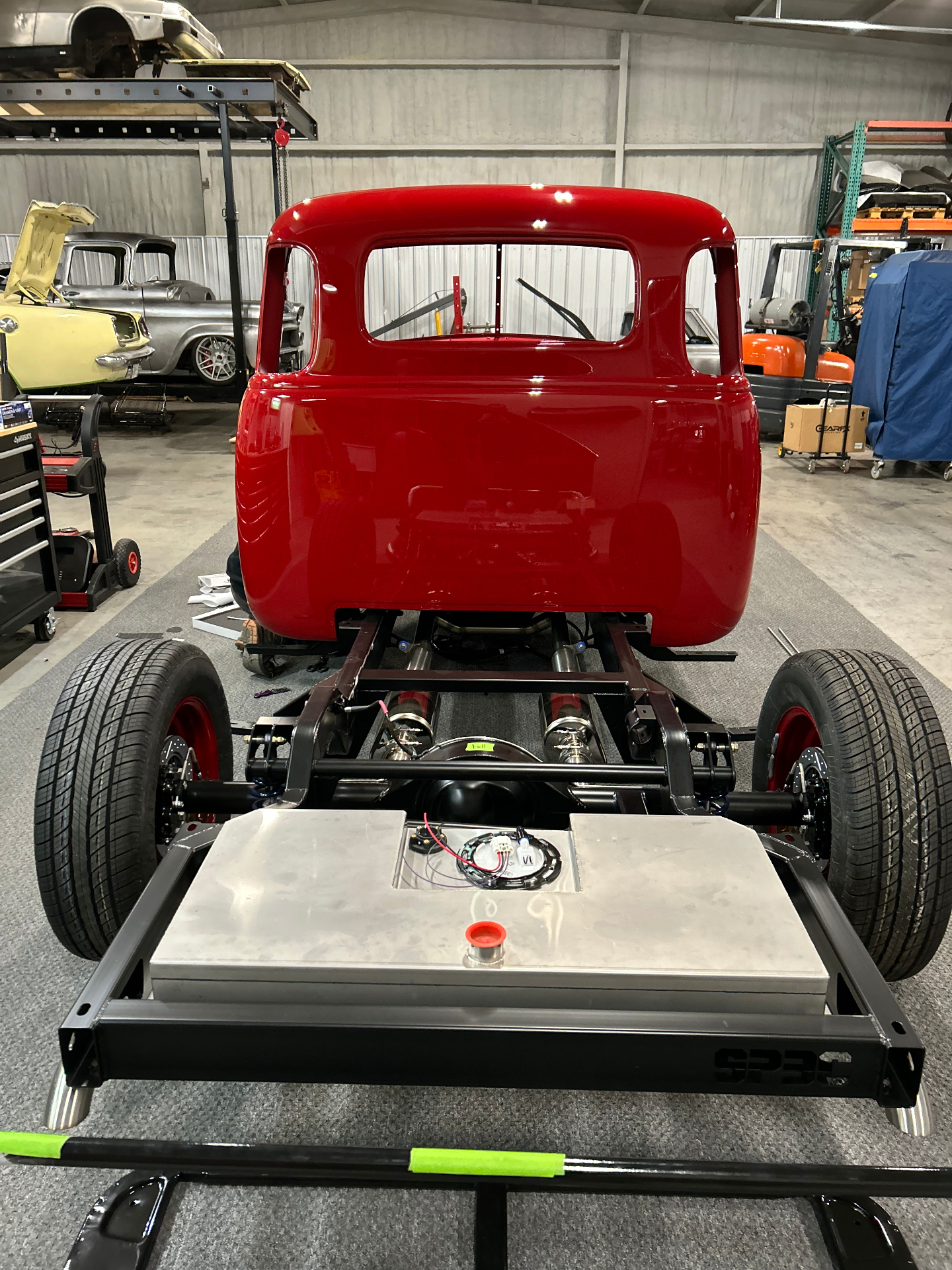 Cab set back down on the SPEC chassis — rear view showing the coilovers, driveline, and aluminum fuel tank tucked between the rails.