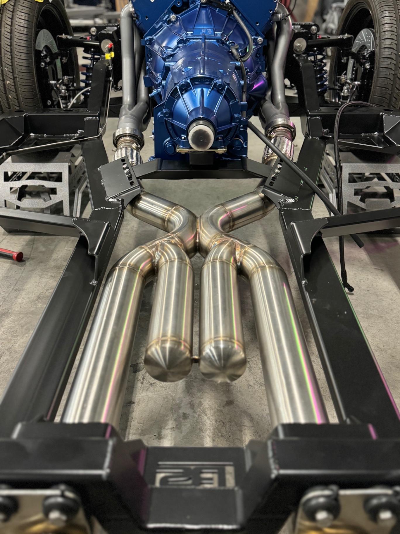Custom stainless X-pipe routed between the frame rails behind the transmission.