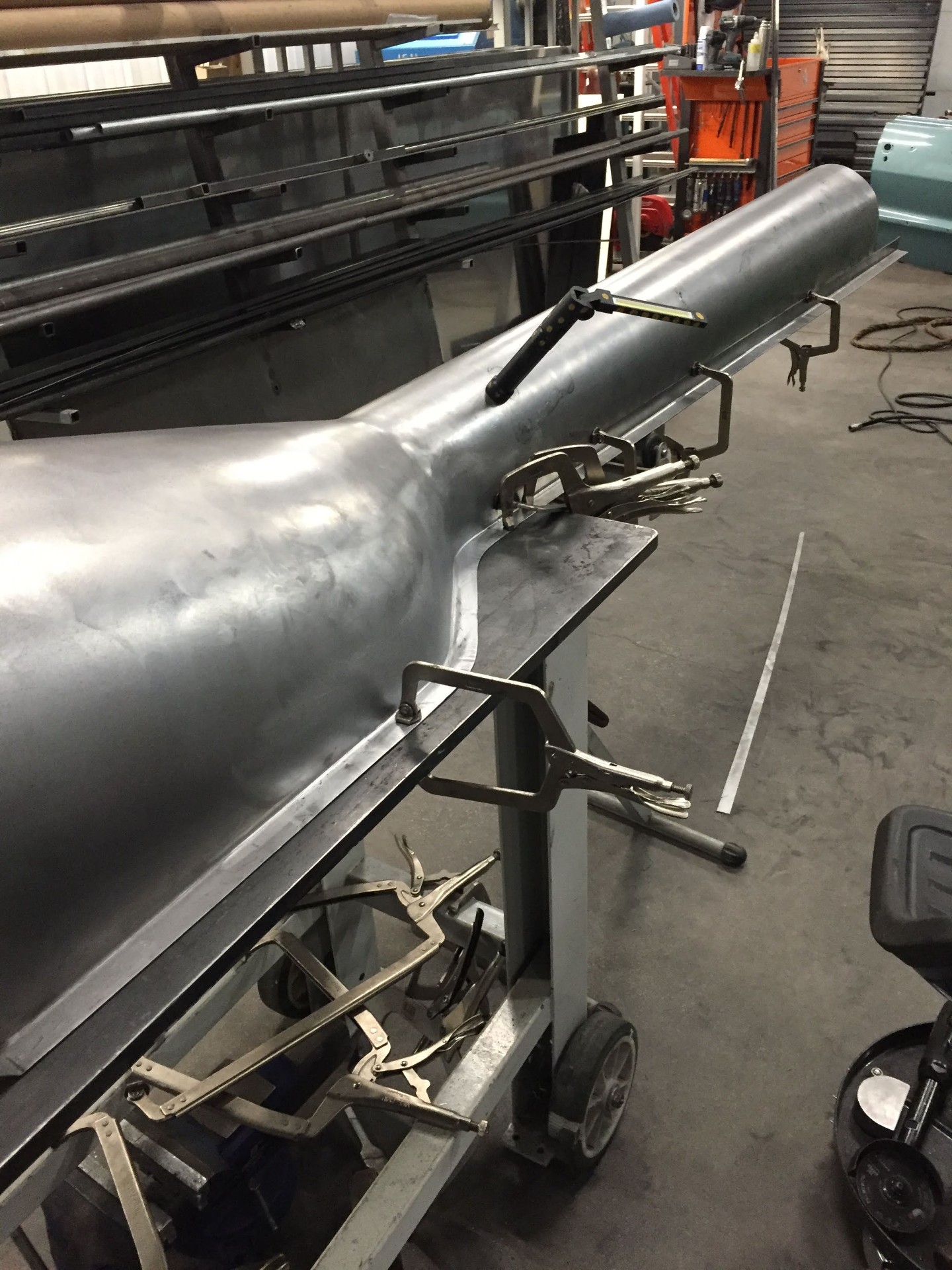 Rolled tunnel section on the bench with the rocker flange clamped for tacking.