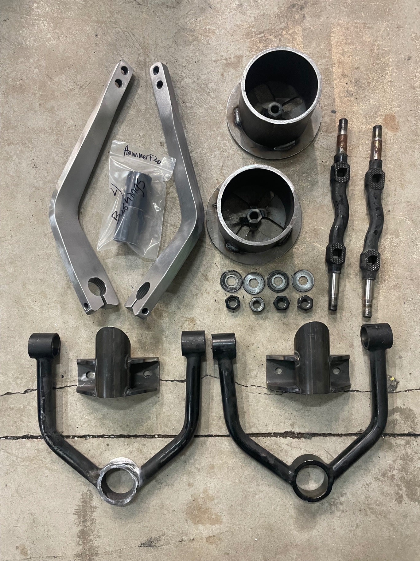 Front suspension parts before coating — raw arms, spindles, and cups.
