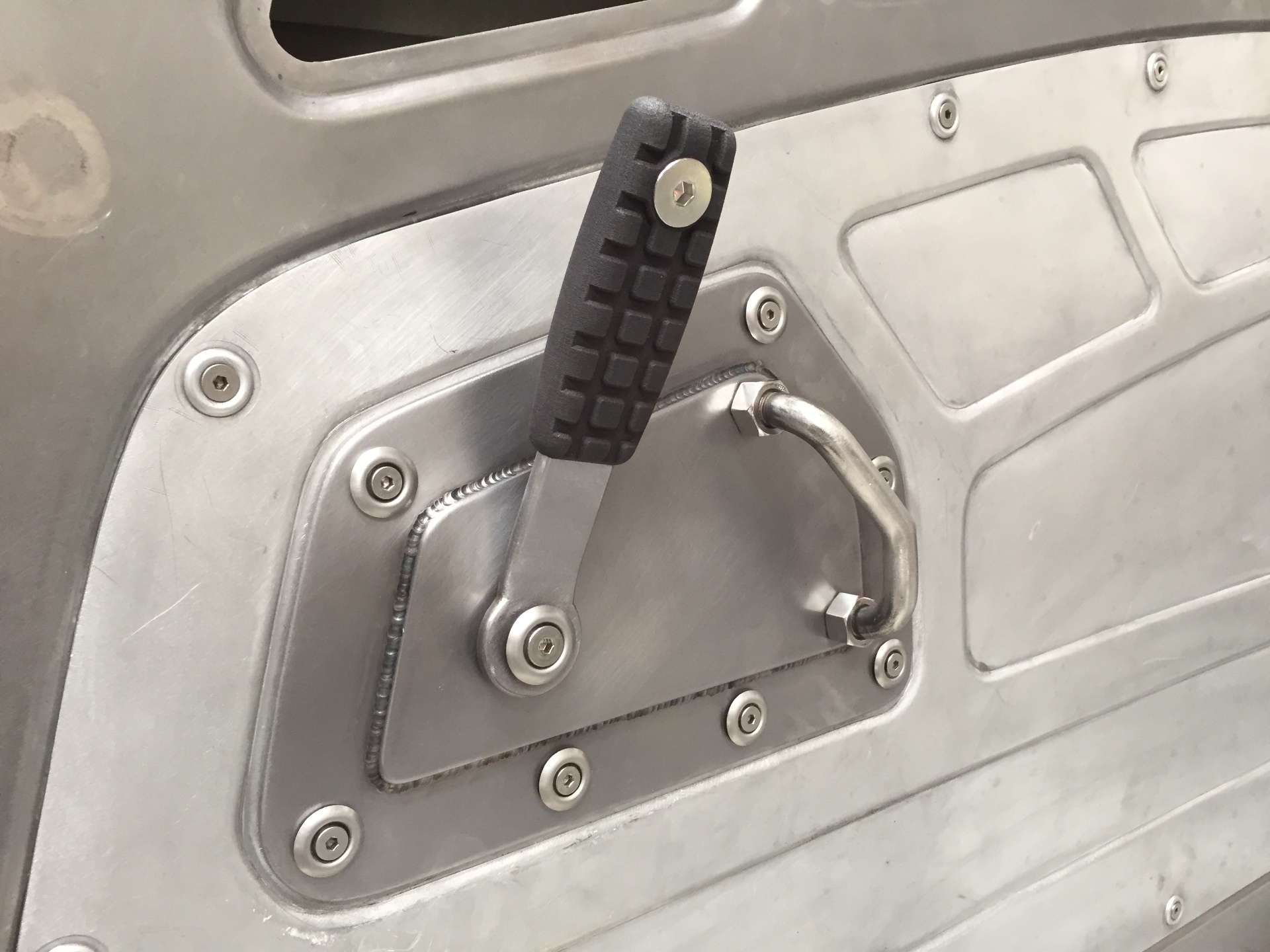 Pedal lever detail — 3D-printed handle on a fabricated arm through a bolted access panel.
