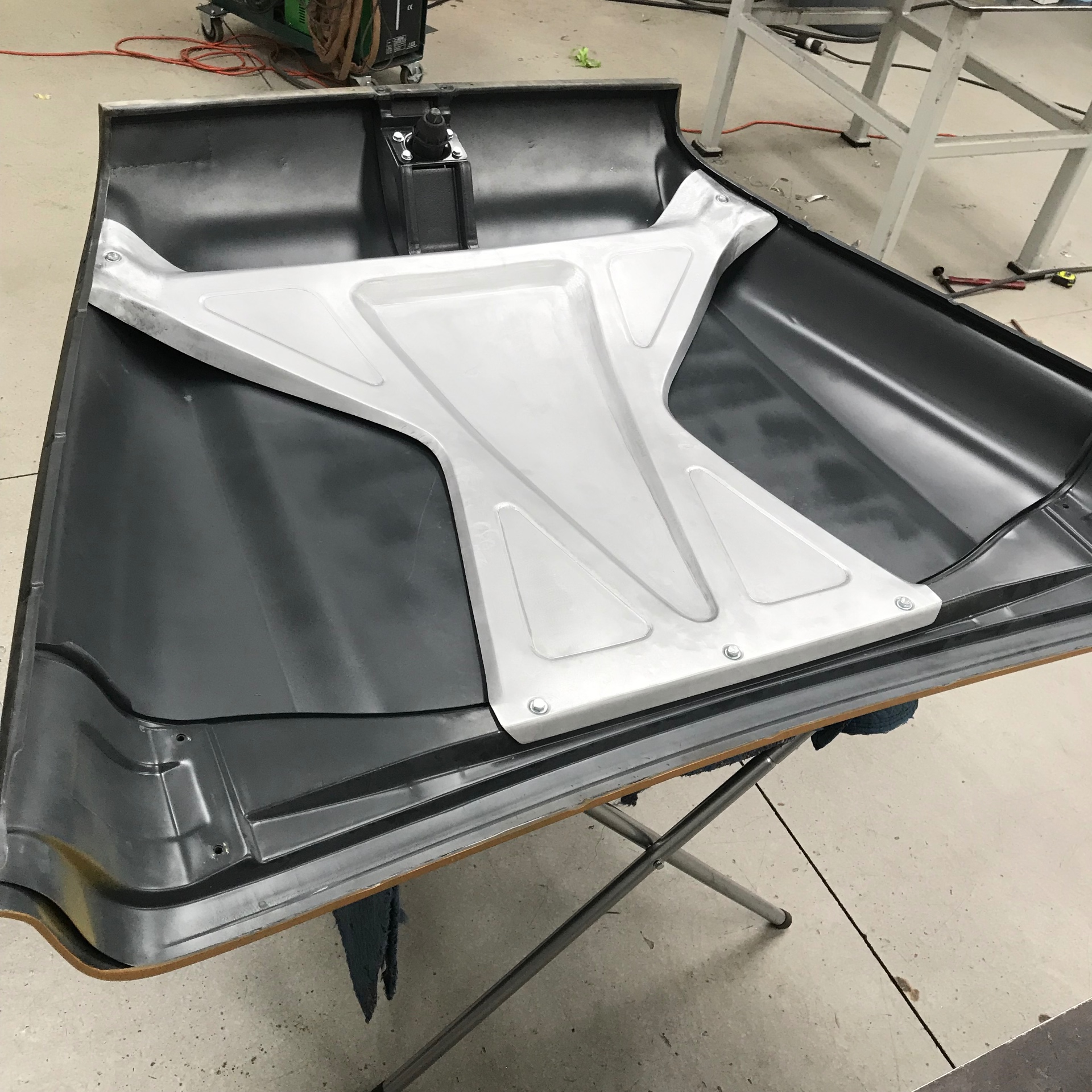 Custom hand-shaped aluminum under-hood brace by Levi — formed with a bead roller and planishing hammer, no welding, just shape and form.