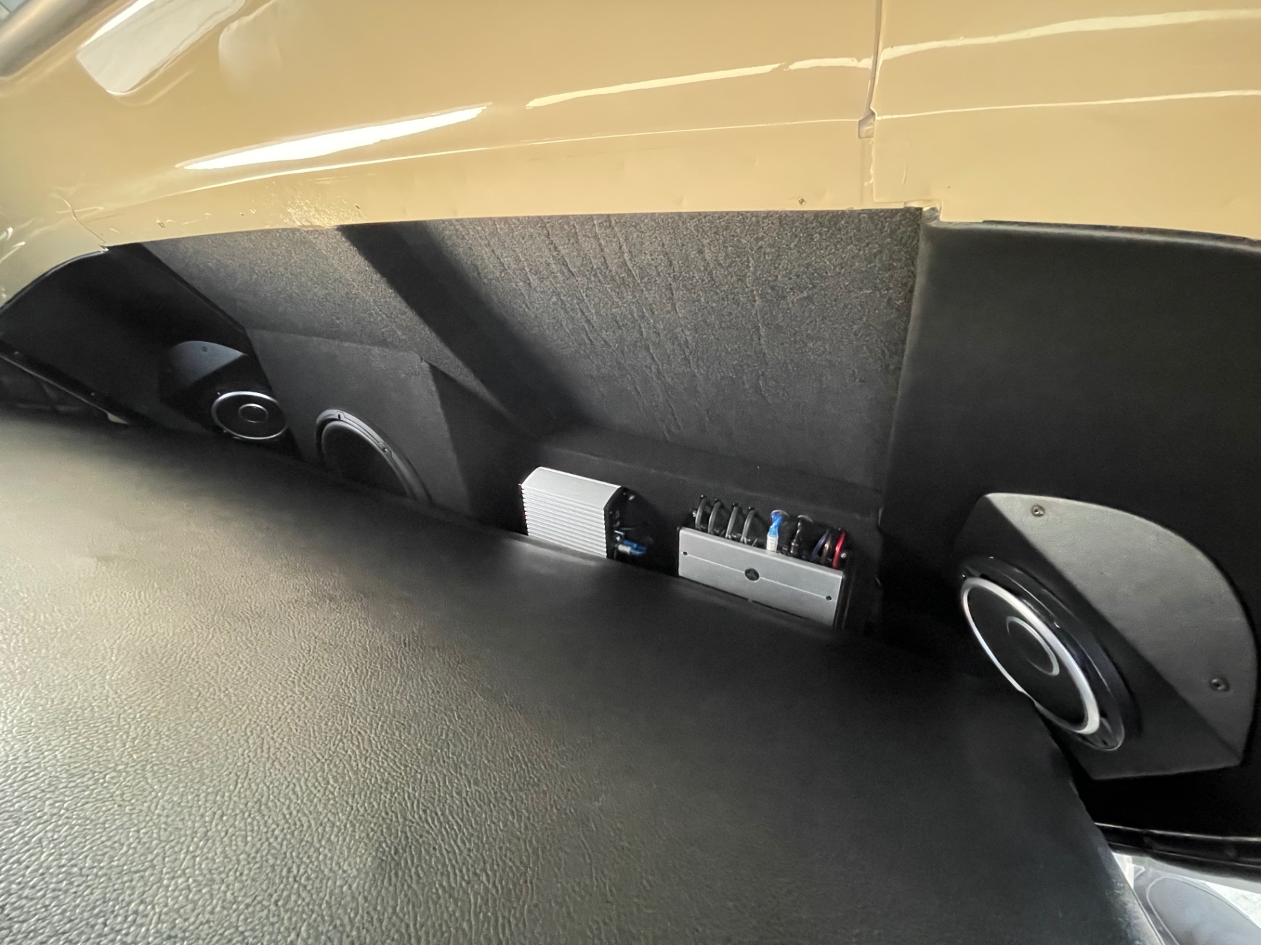 Behind-the-seat audio — JL Audio amps and speakers tucked out of sight, with more in the kick panels.