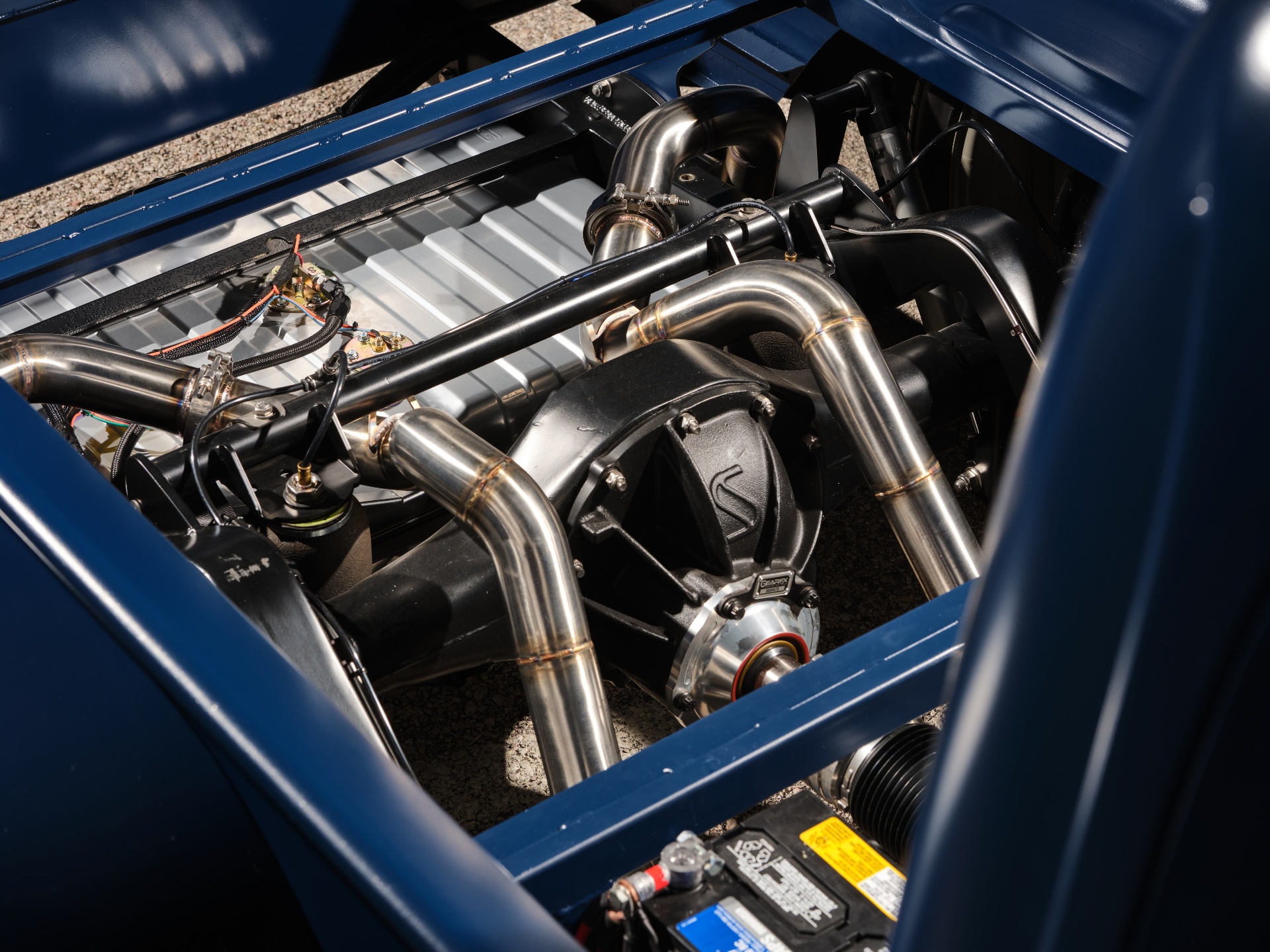 Stainless exhaust detail — TIG welded bends routed around the rear end and driveshaft.