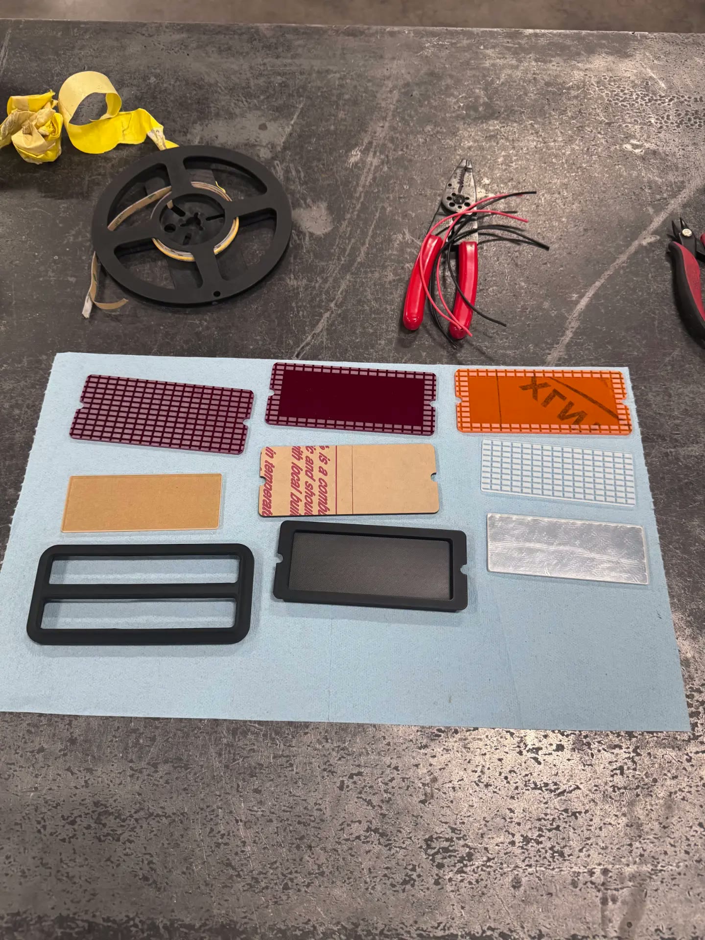 Engraved lens samples, diffusers, and printed housings laid out for testing.