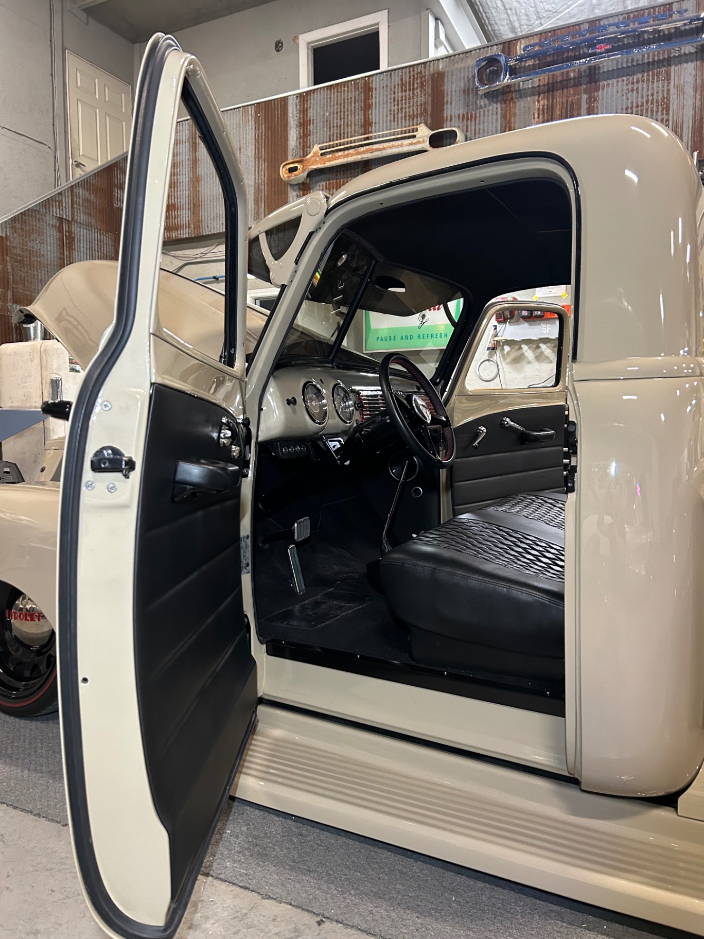 Cab with new panels open — thin edges, painted upper flowing into leather lower, diamond bench behind.
