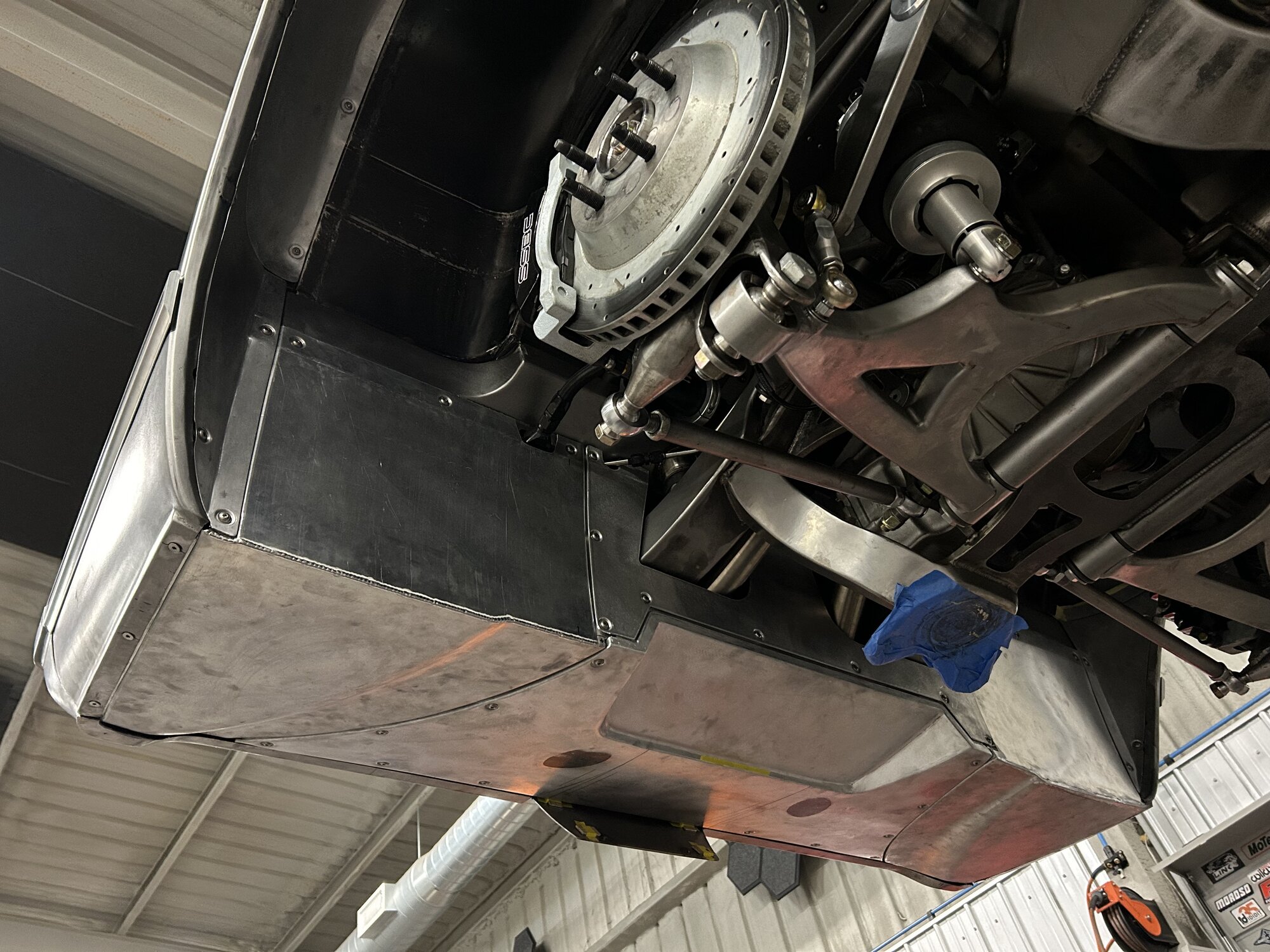 Underside on the lift — hand-fabricated belly panels and chassis.