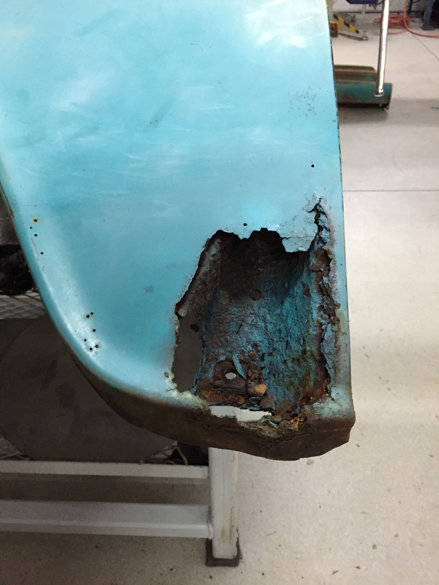 Lower cab corner as it arrived — rust-through and paint history that would later be preserved, restored, and clear-coated rather than replaced.