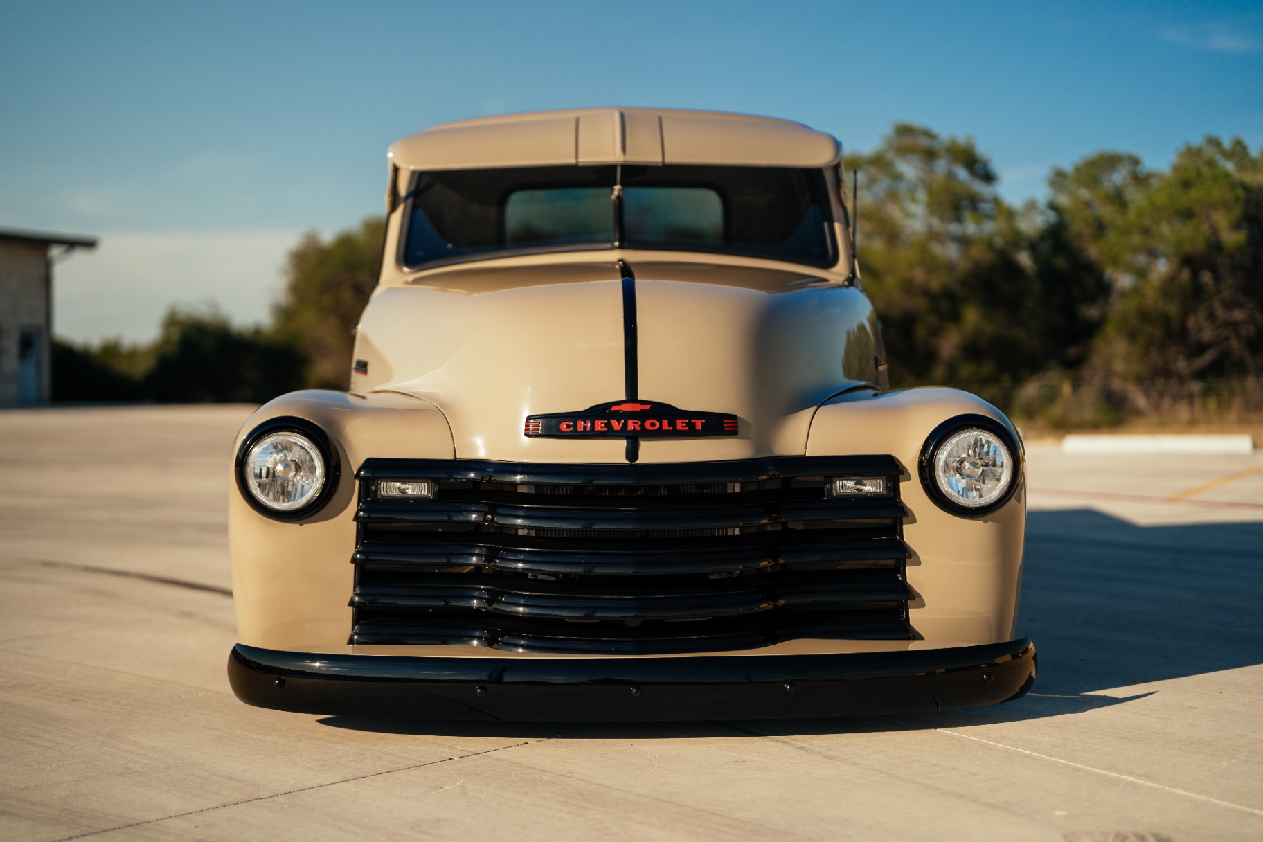 Dead-on nose — black grille bars and red Chevrolet badge against the tan.