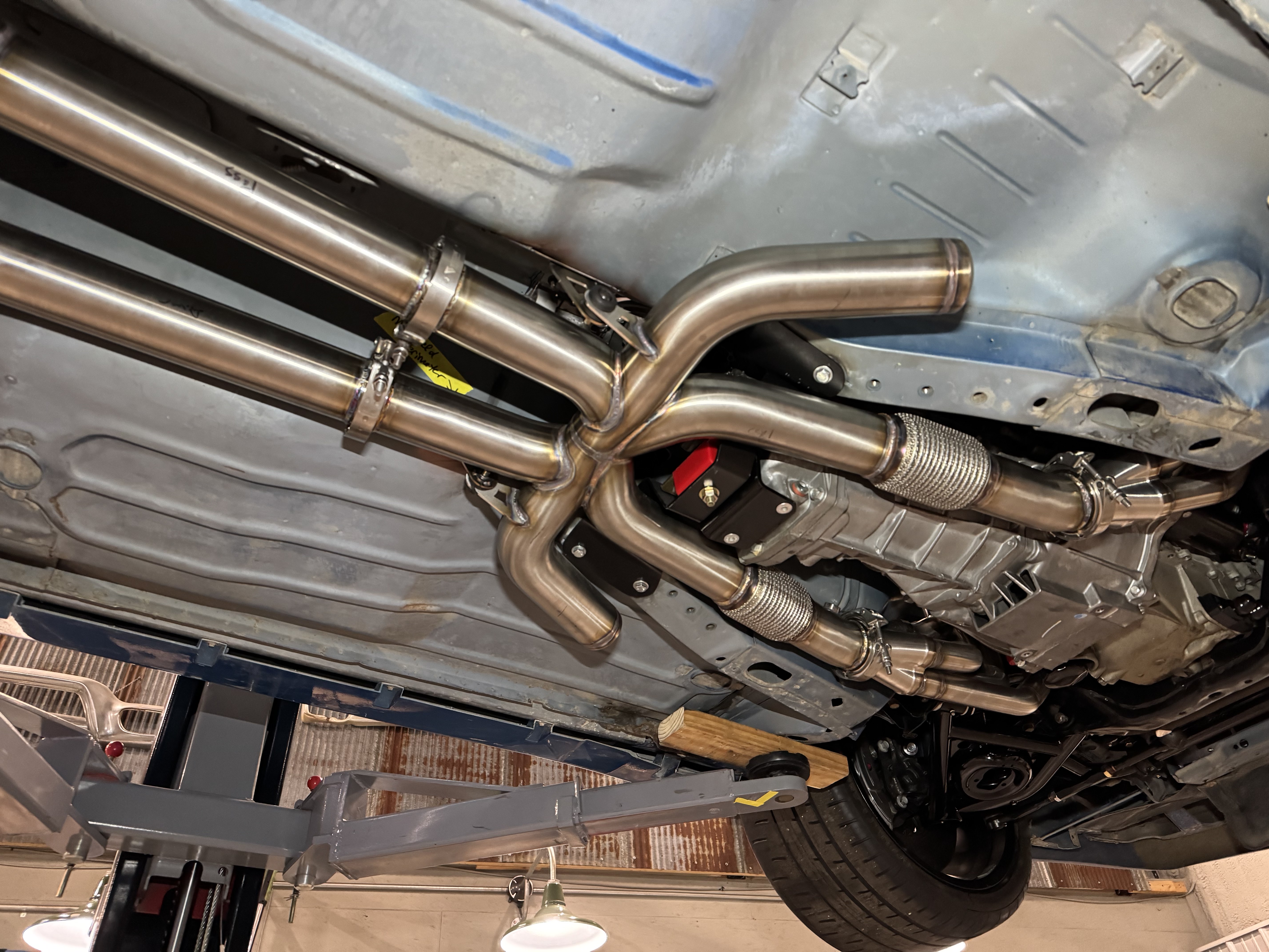V-band clamps, flex joints, and the forward-facing resonance tubes converging at the crossover.