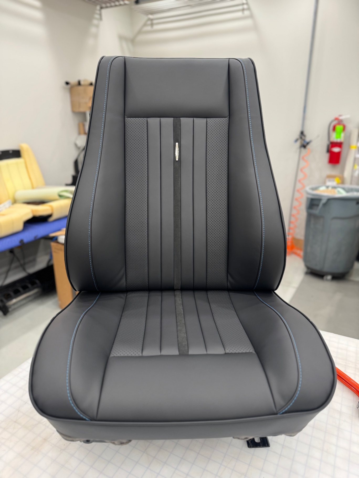 Bucket seat front — Alcantara stripe, perforated leather, blue accent piping.