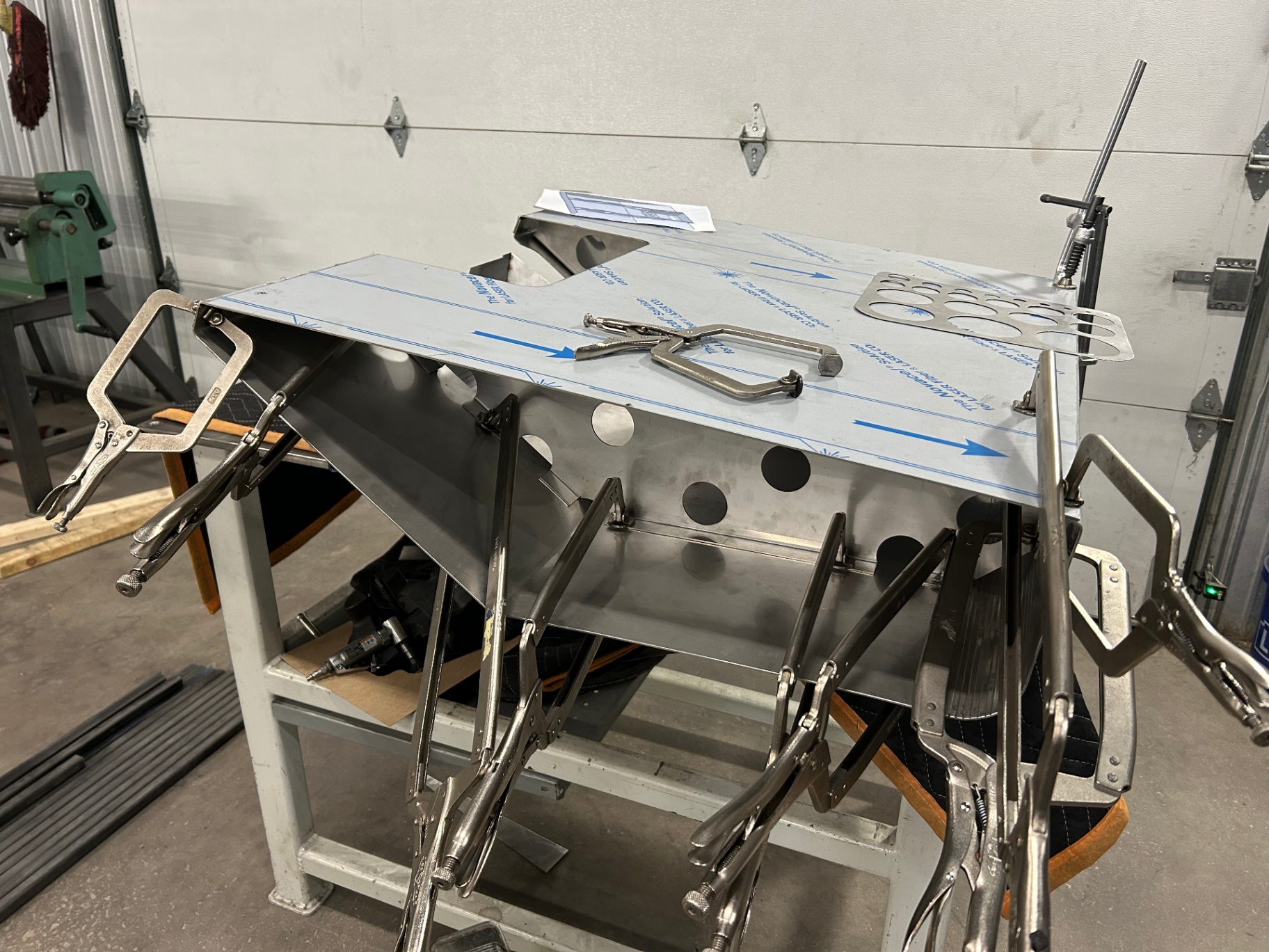Laser-cut stainless panels clecoed together on the bench for a dry mockup.