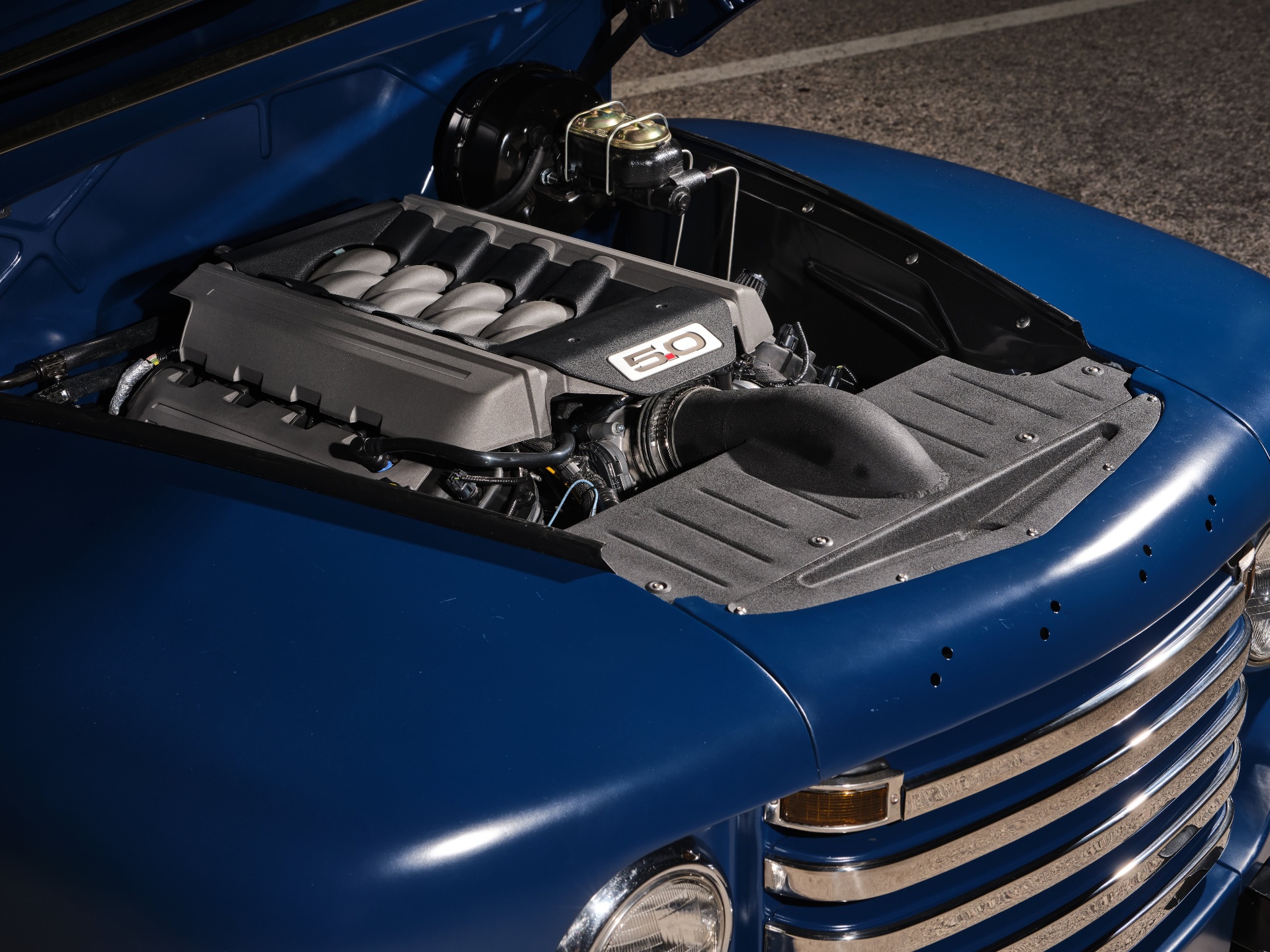 Ford 5.0L Coyote V8 under the F1 hood with a clean coil-cover treatment and painted inner fender panels.