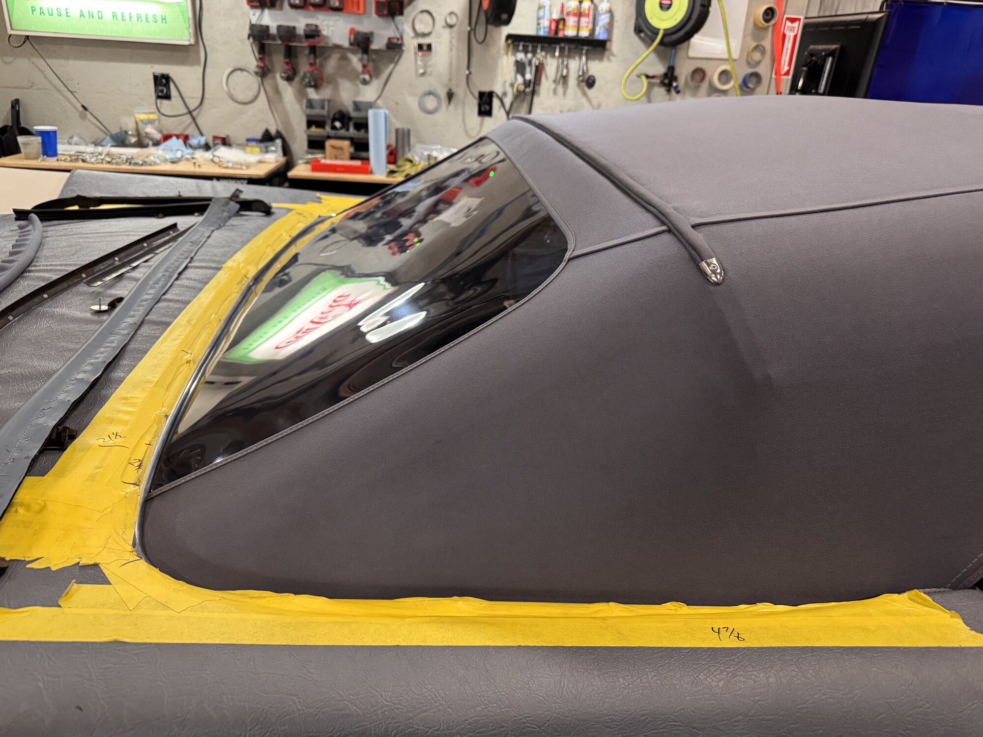 Rear quarter window detail — canvas hugging the glass with the stainless pull tab and taped trim line
