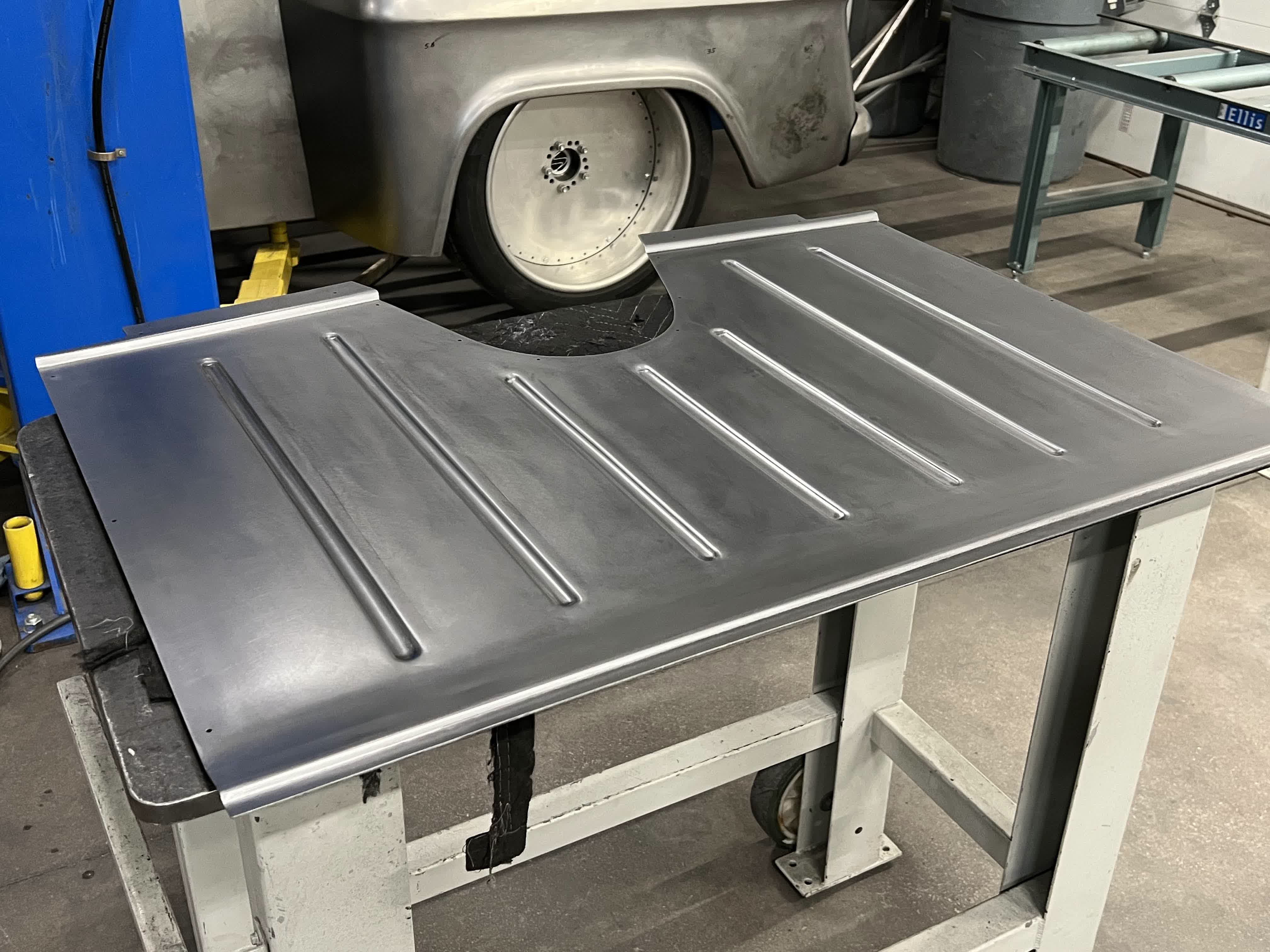Fresh 14ga rear seat floor pan on the bench after being run through the Pullmax.