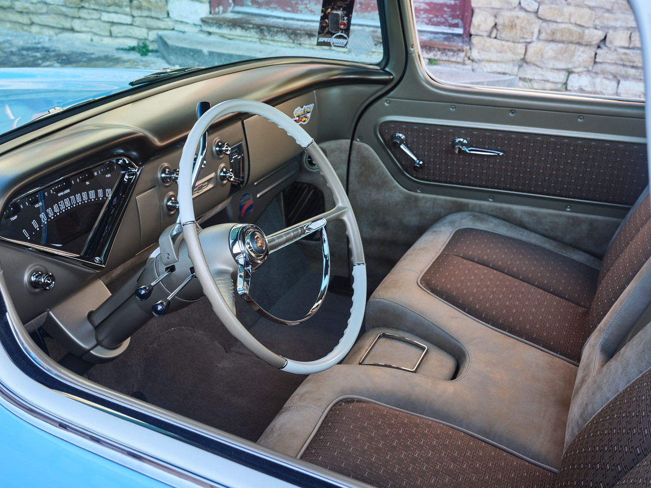 Driver's side interior — Jay Schluter's foam and stitch work on the custom C10 bench, satin brown metallic dash top, and the white steering wheel against the two-tone cabin.