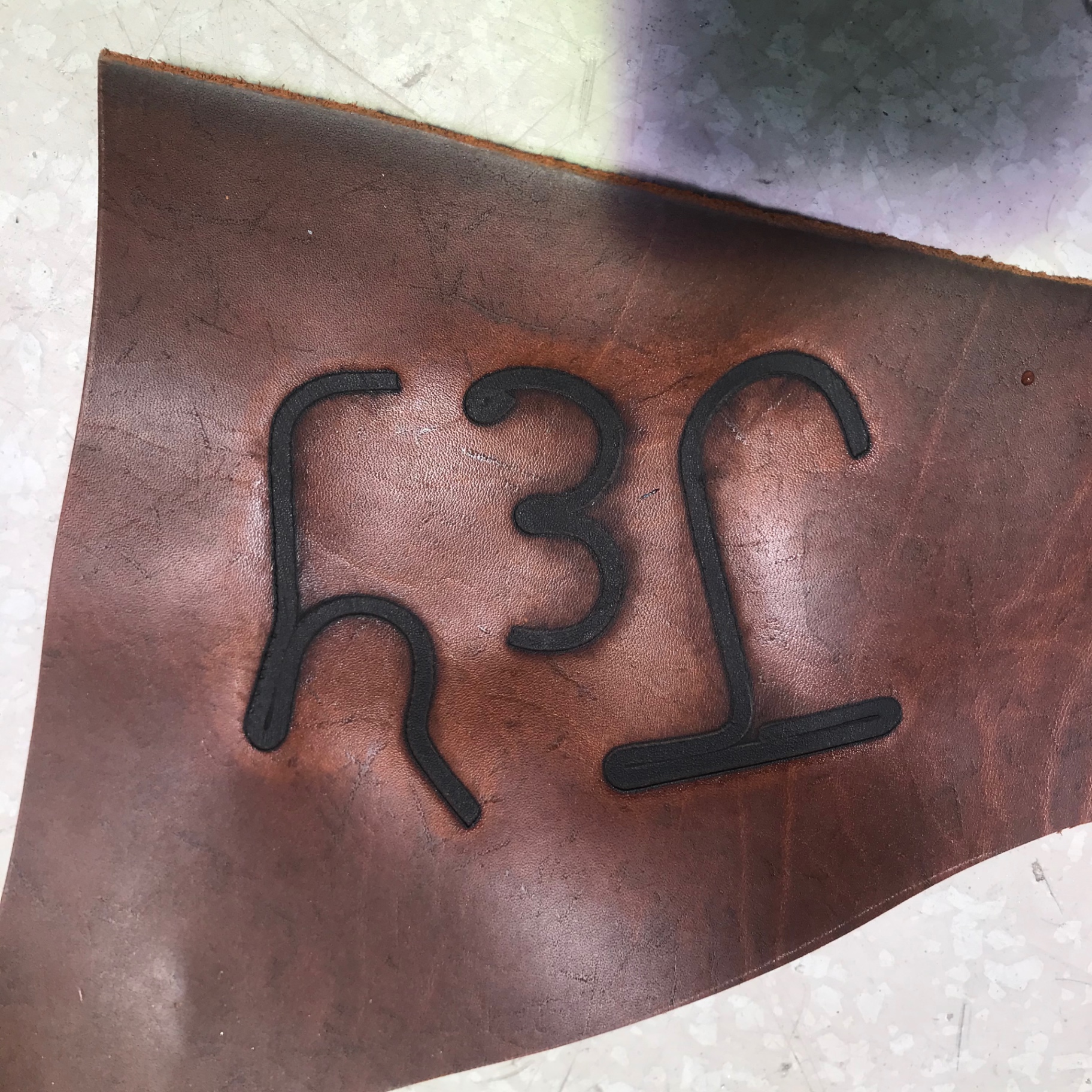 Burn test on leather — clean, even impression across all three characters.