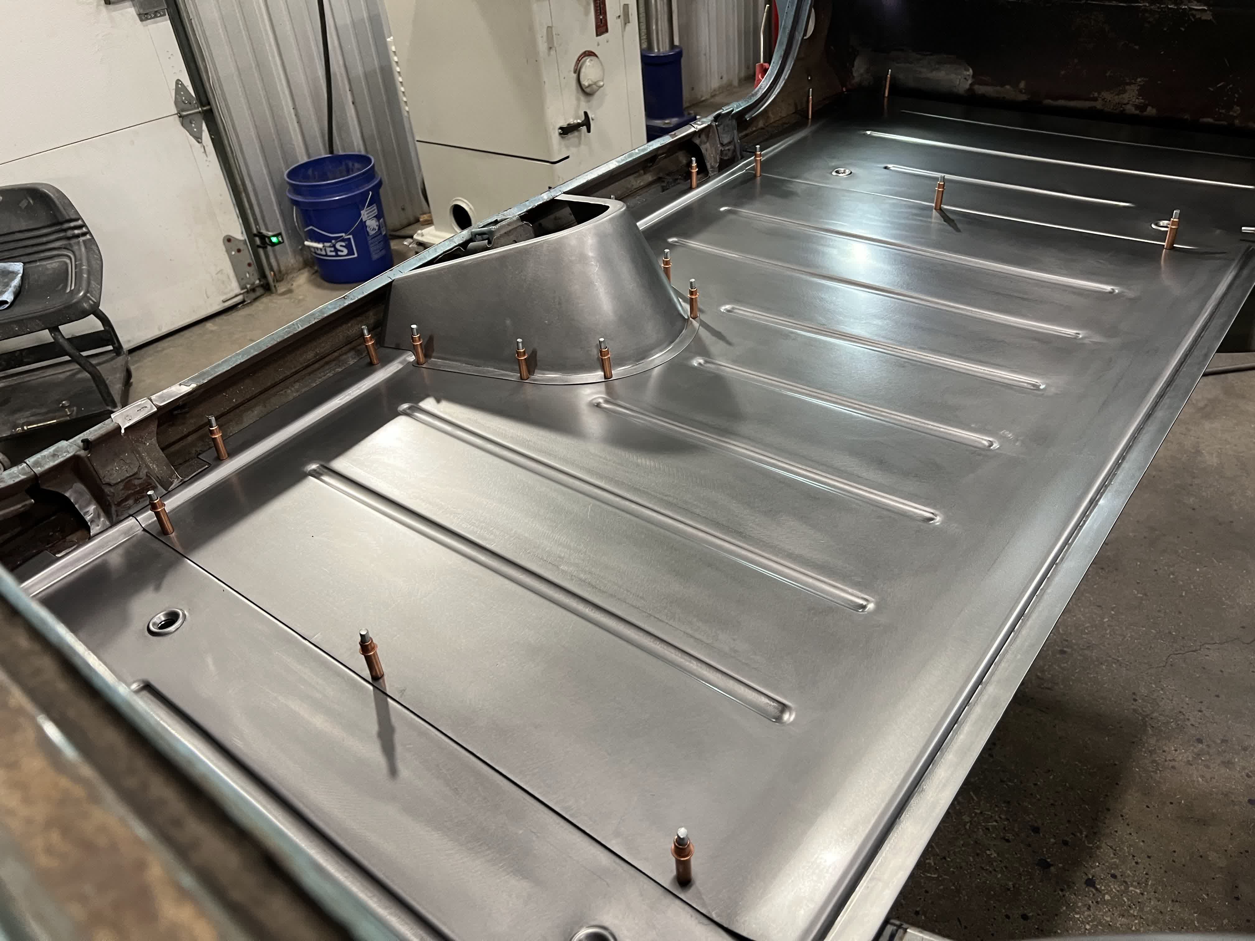 Full cabin floor with driveshaft tunnel cleco'd in — every panel stamped in-house.