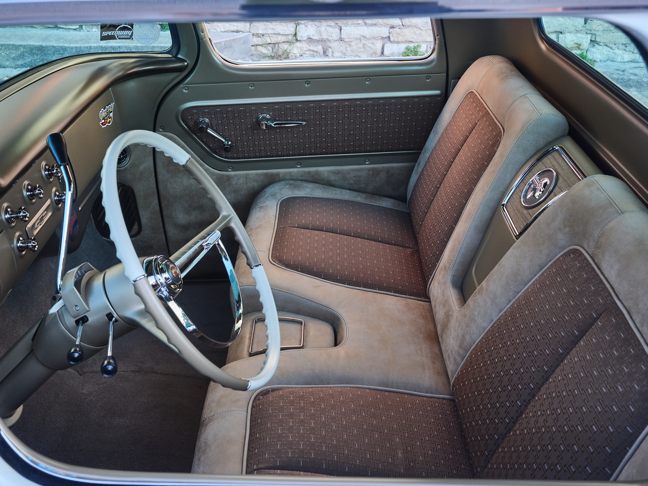 Passenger-side view of the custom C10 bench — leather bolsters with NOS 1955 Bel Air fabric inserts, Pontiac-tribute headrest emblem, and body-color painted panels.