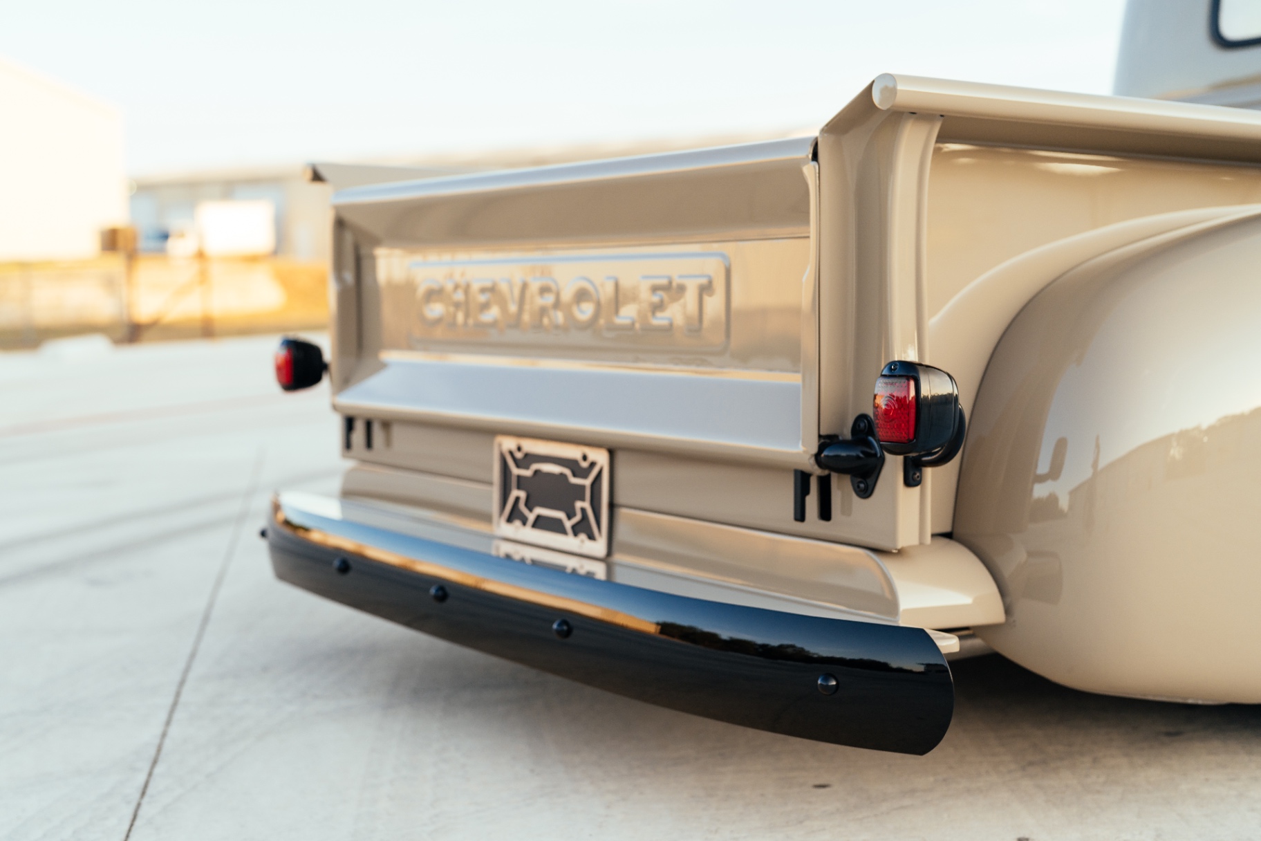 Tailgate detail — stamped Chevrolet script, HF tailgate stops, gloss black bumper.
