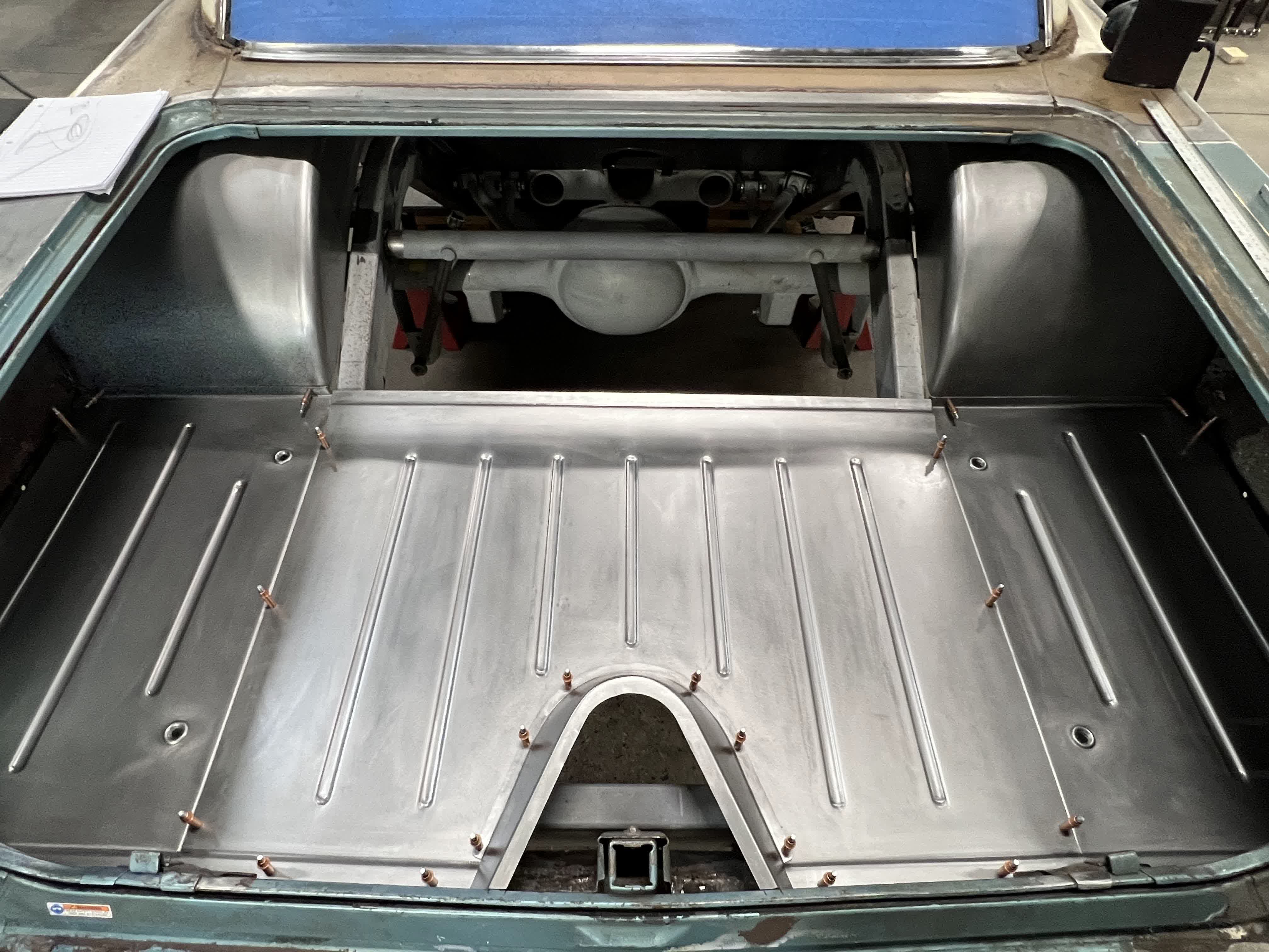Trunk floor clecoed in place with the rear end and Panhard bar visible above.
