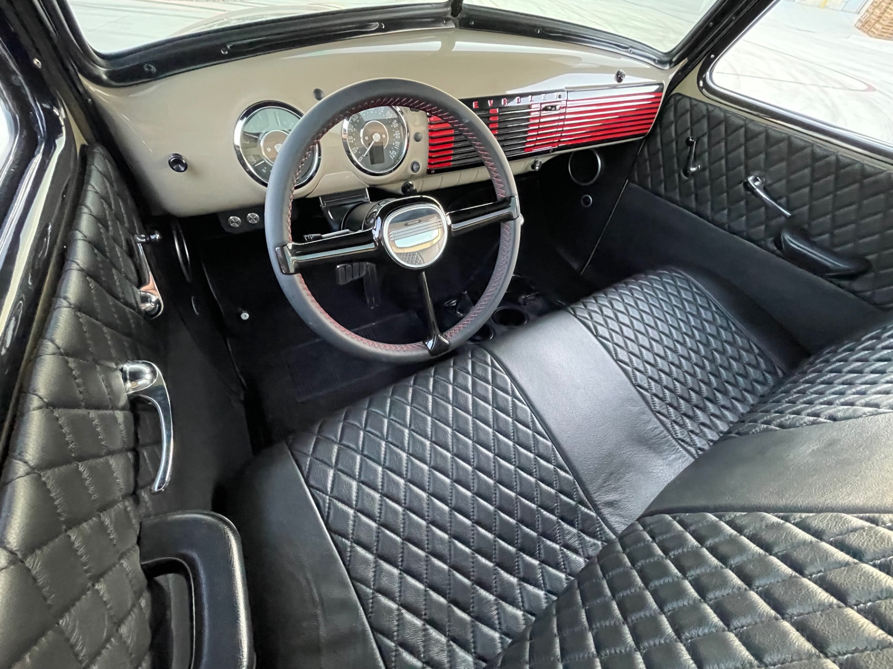 Cab overhead — diamond-stitched bench, black carpet, red dash grille peeking through the wheel.